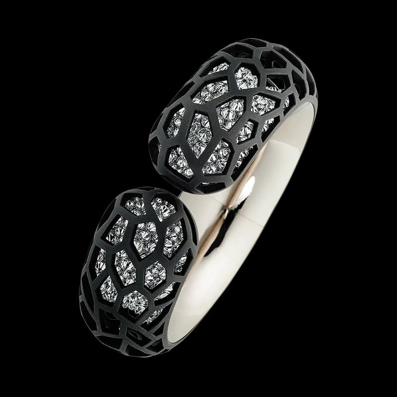 A sculptural dark and pale metal Harmony bangle with diamonds set into its open ends.