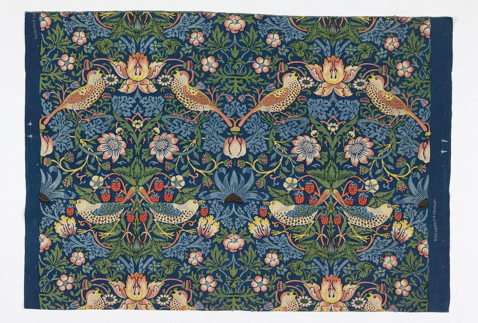Strawberry Thief textile with paired birds, curling foliage, flowers and red fruit on a dark blue ground.