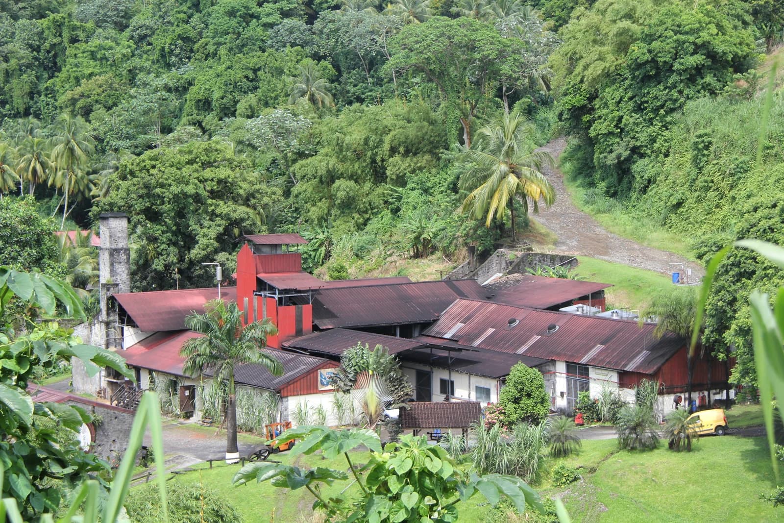 Red-roofed buildings of the J.M distillery at Macouba sit below a densely green hillside in Martinique.