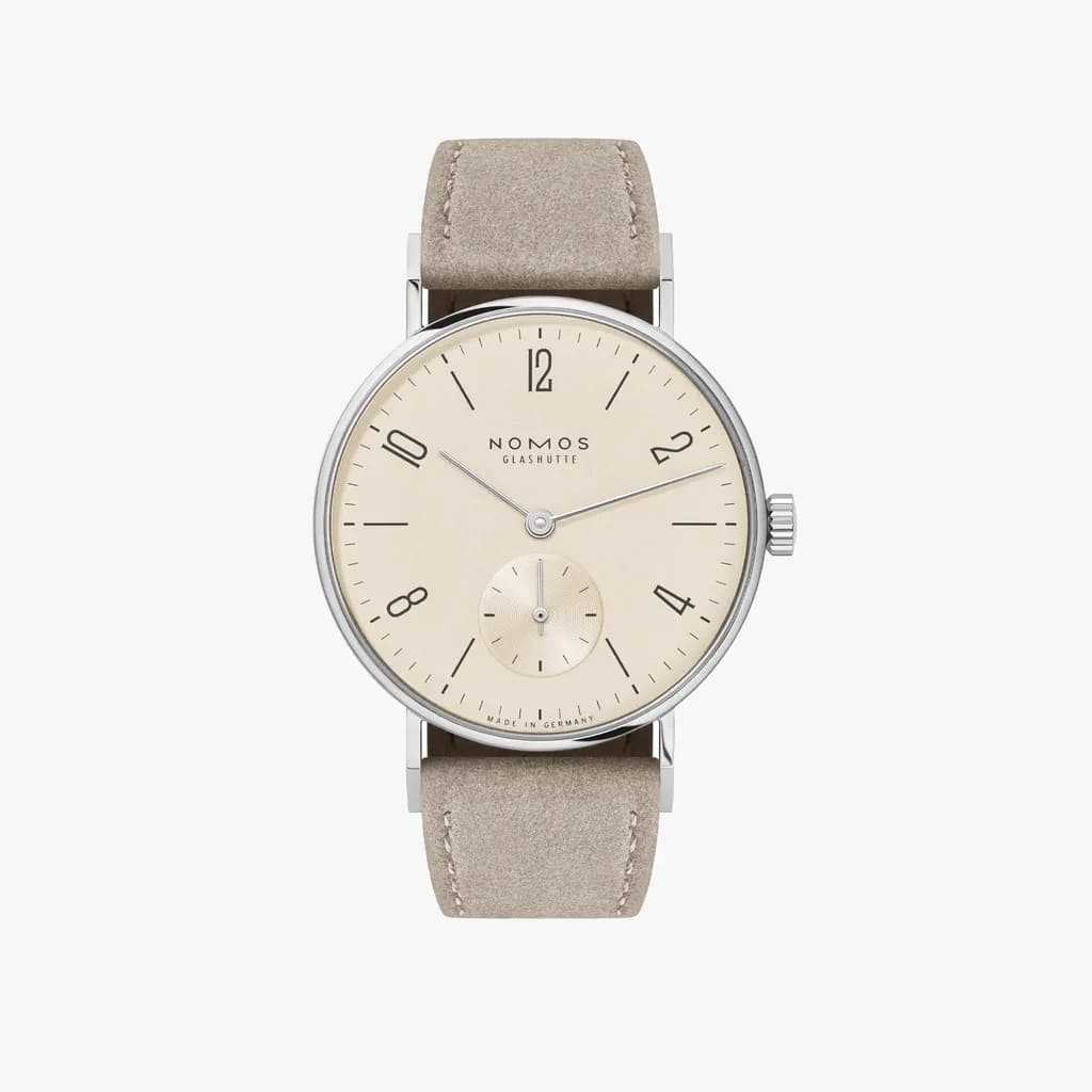 The champagne dial, slim steel case and pale strap of a NOMOS Tangente 33 in a straight-on studio product view.