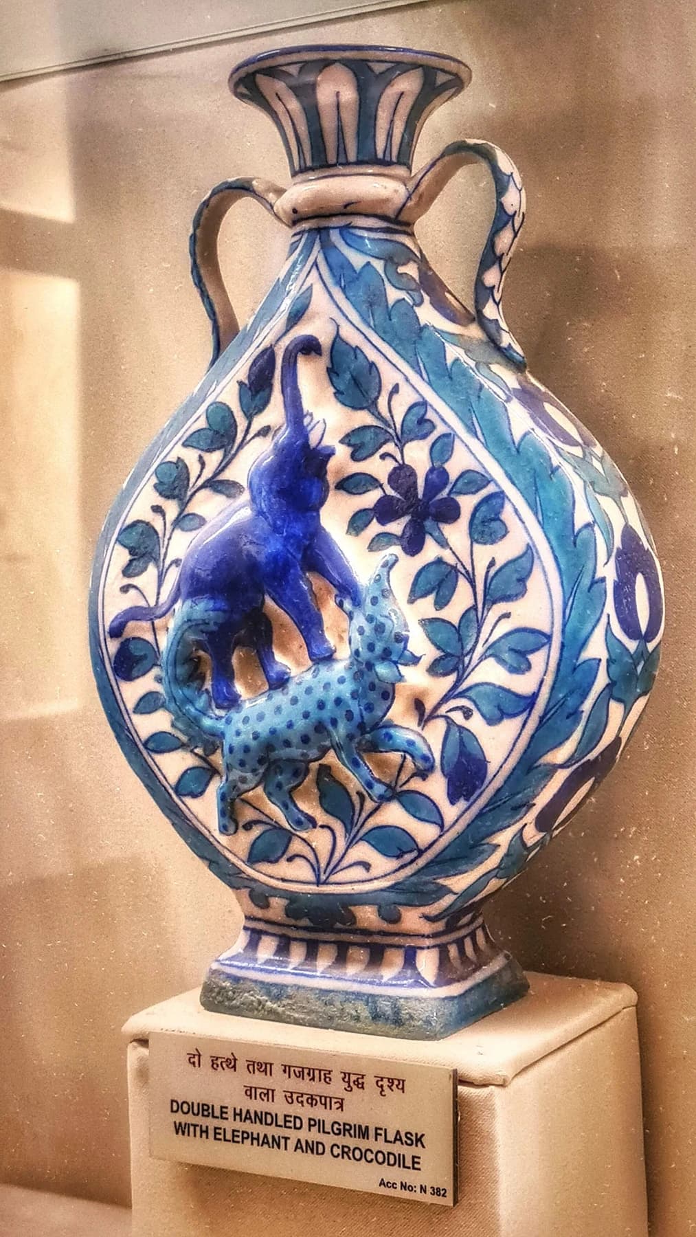 A blue-and-white pilgrim flask with two handles and painted animal and foliate decoration, displayed at the Albert Hall Museum in Jaipur.