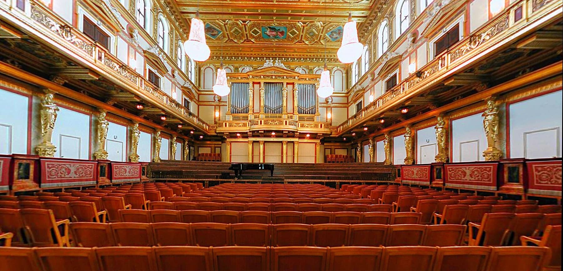 The Musikverein Golden Hall viewed towards its organ and stage, with rows of red seats, gilded details and an ornate ceiling.