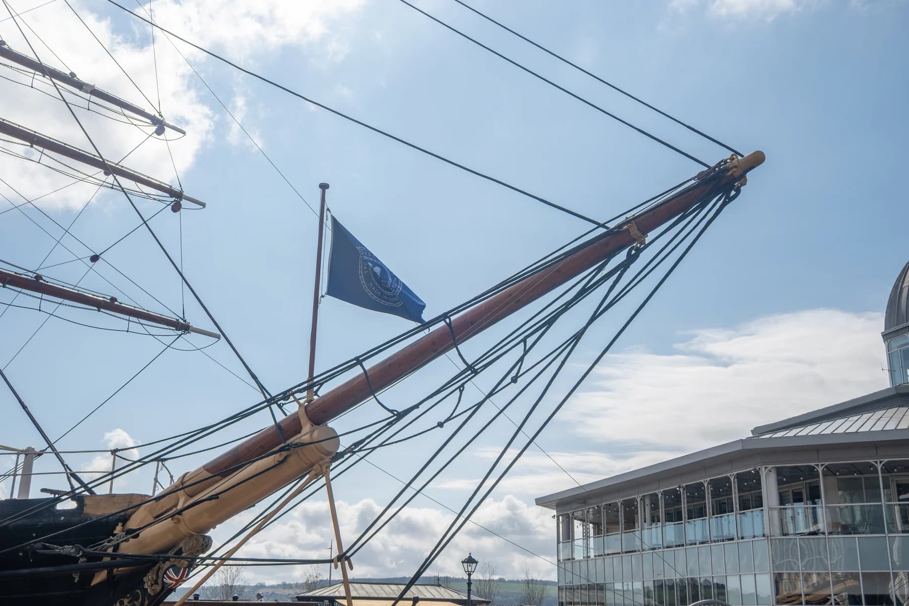 RRS Discovery’s timber bowsprit and rigging stretch diagonally across the sky above the Dundee visitor centre.
