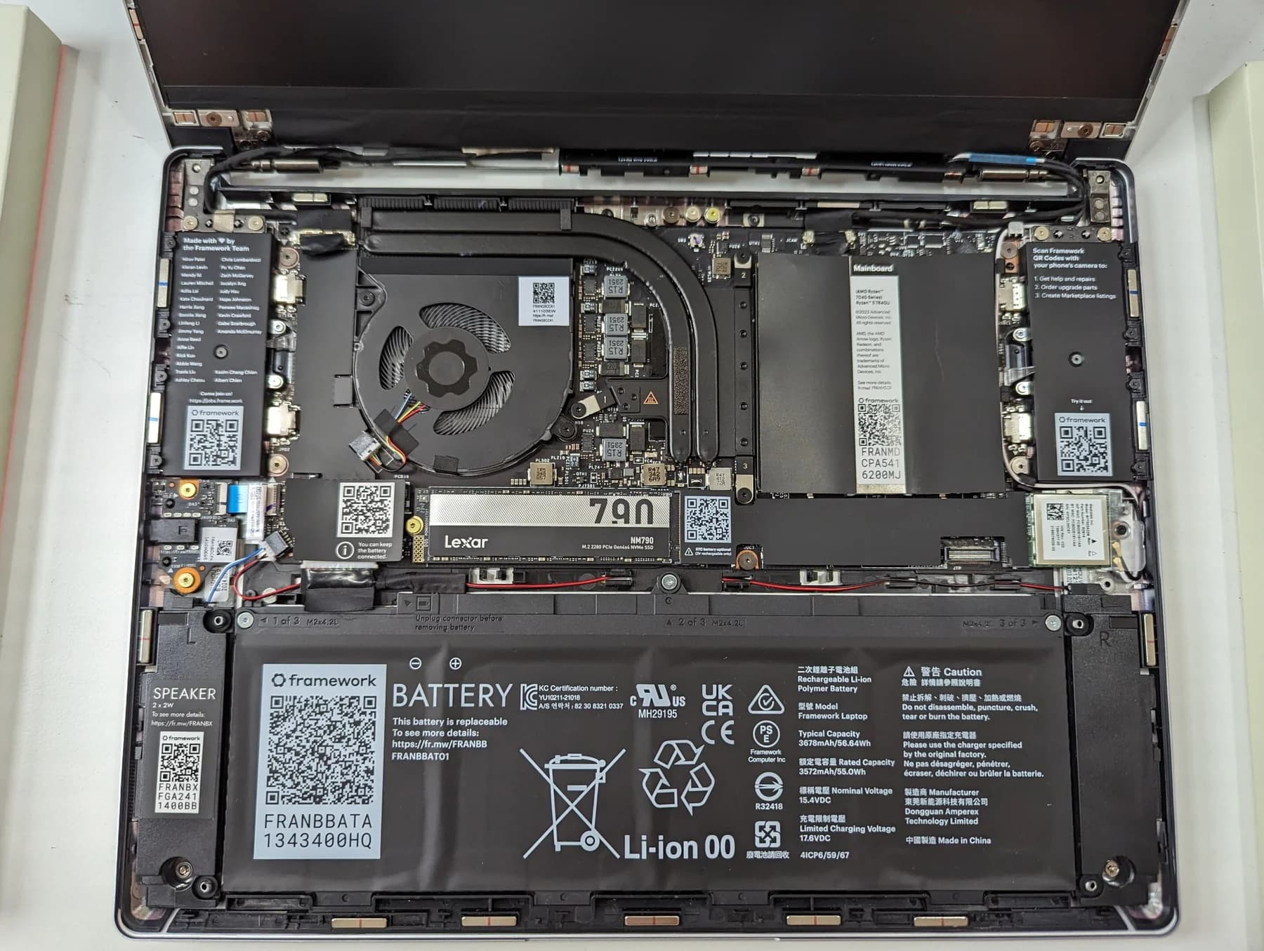 The opened base of a Framework Laptop 13, with the battery, cooling fan, mainboard and storage visible as separate components.
