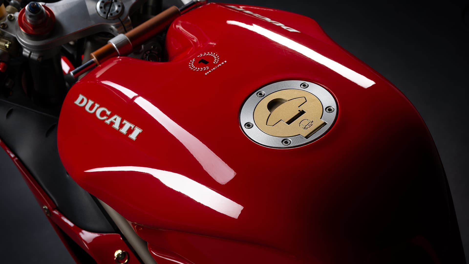 Close view of the red Ducati 916 tank, its white model lettering and the cockpit behind it.