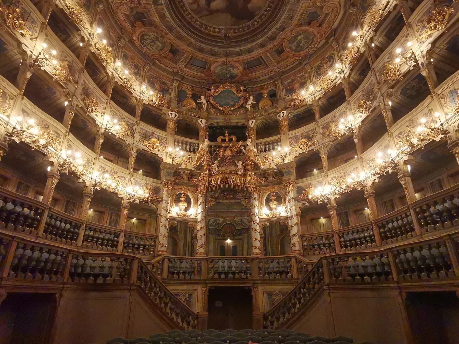 The ornate tiers and painted ceiling of Bayreuth’s Margravial Opera House, with gilded columns, sculpted decoration and rows of empty audience boxes.