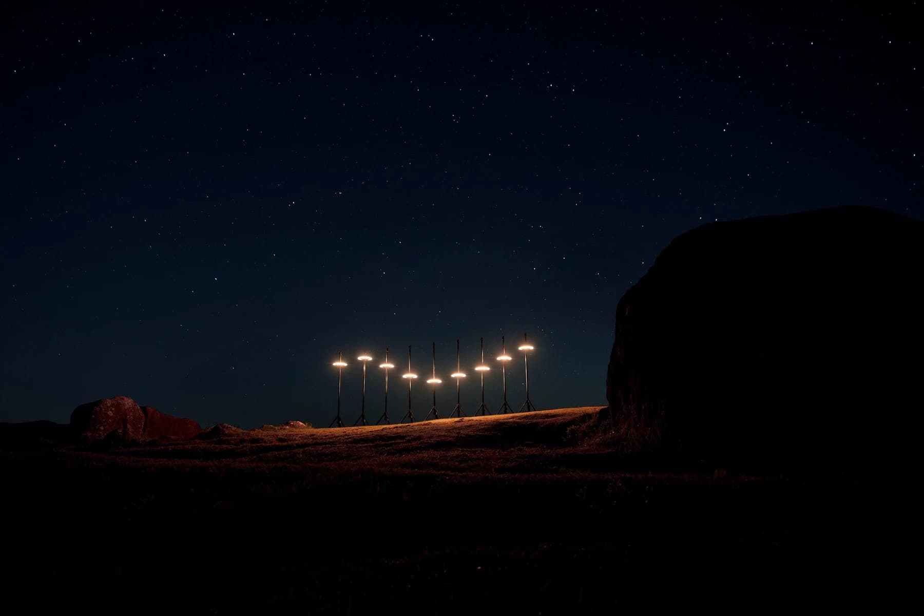 FLIGHTGRAF’s LOOP luminous discs arranged at different heights in an outdoor rocky landscape after dark.