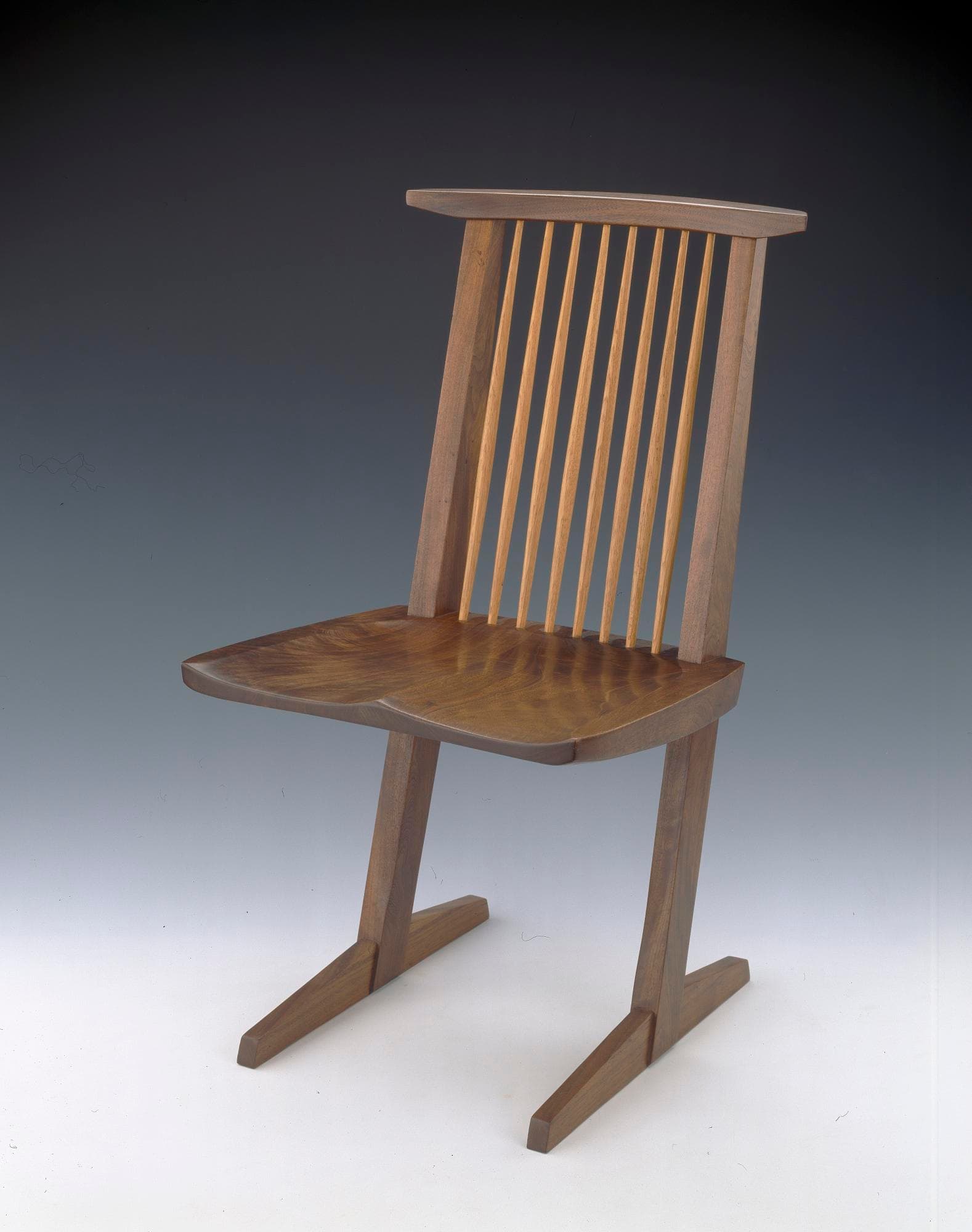 George Nakashima’s 1971 Conoid Chair in black walnut and hickory against a neutral museum background.