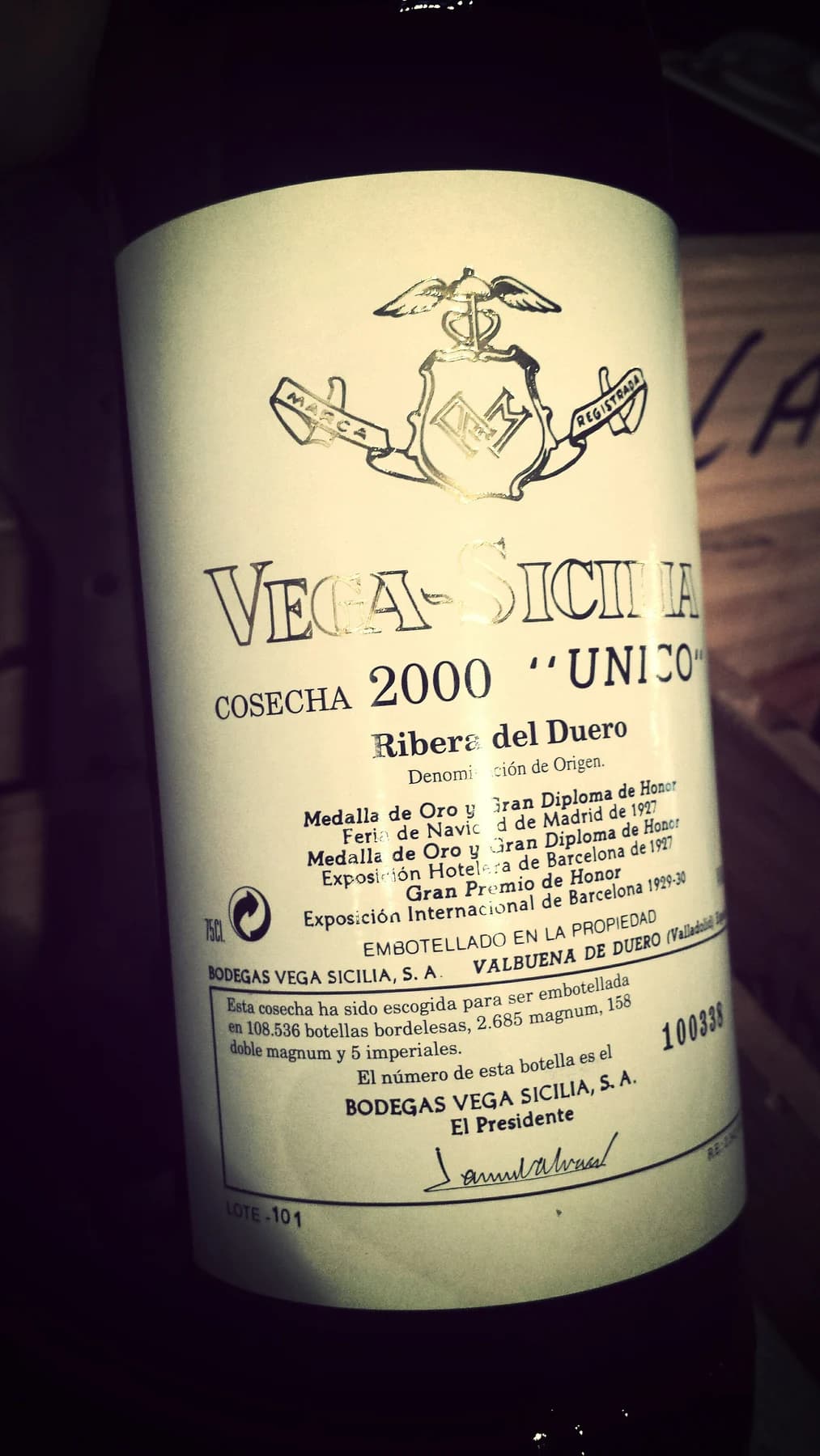 A close, warmly lit view of a Vega Sicilia Único 2000 bottle, with its vintage lettering and illustrated estate label visible.