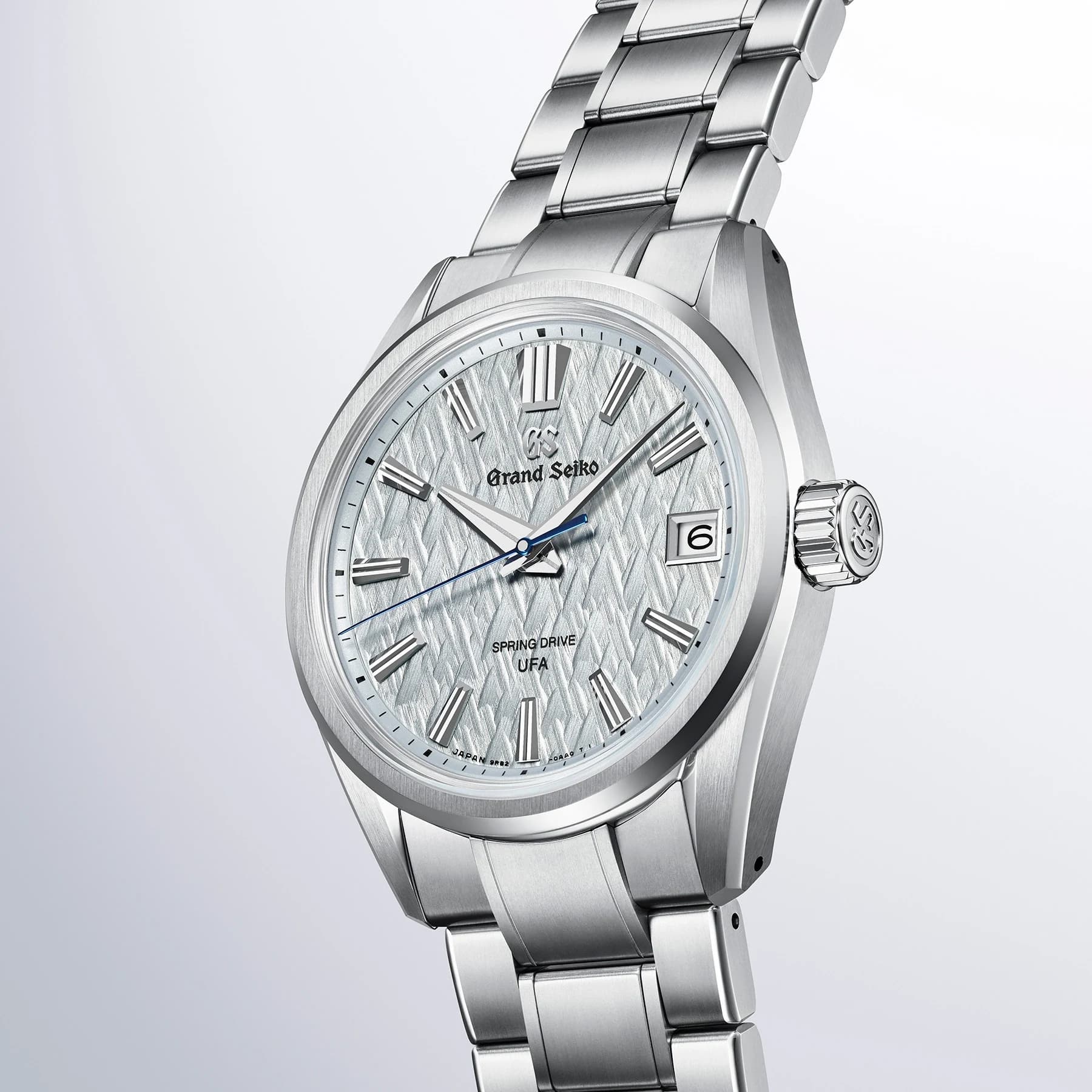An angled close view of the Grand Seiko SLGB003 with a pale ice-forest-patterned dial, blue seconds hand and part of its titanium bracelet.