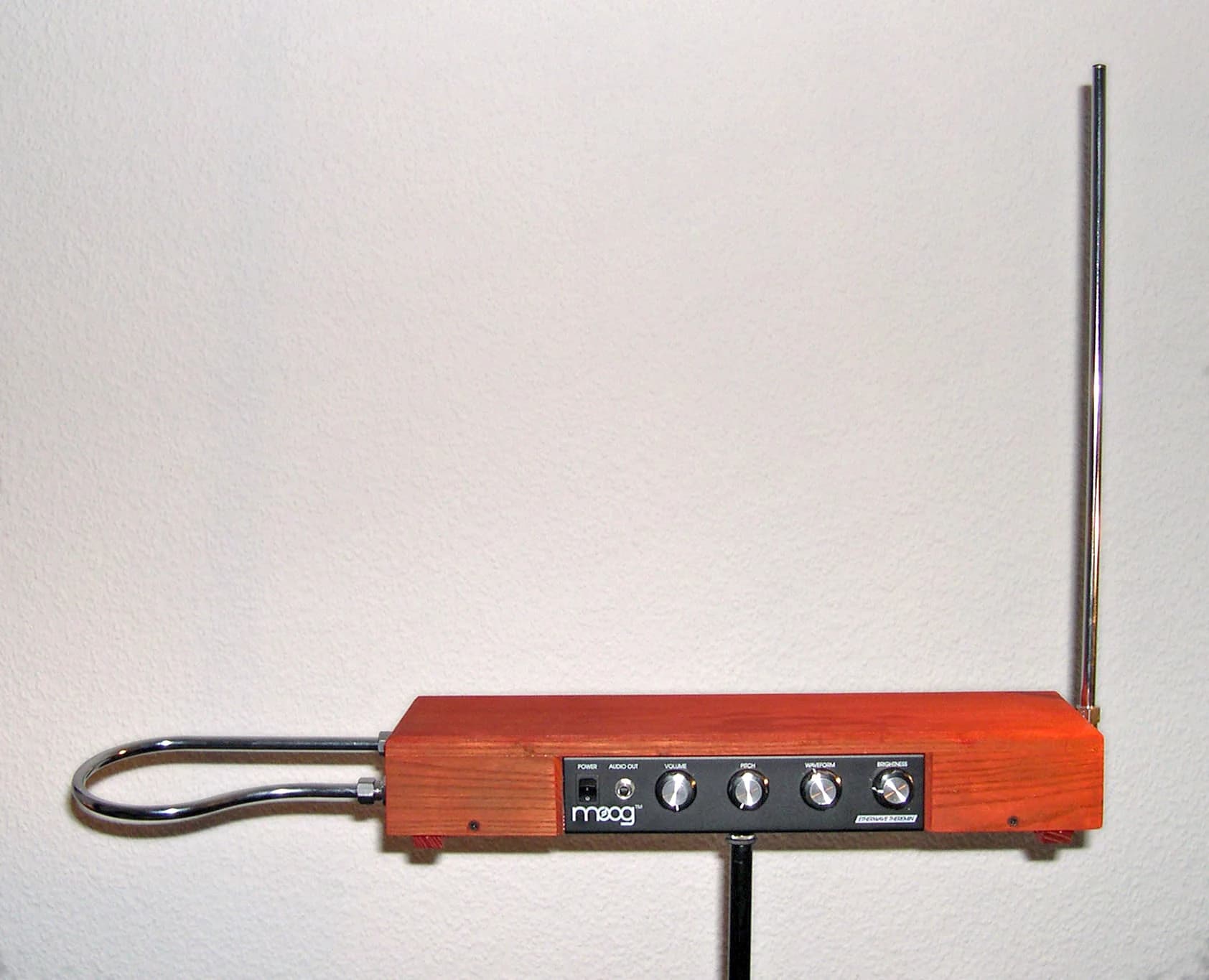 A kit-built Moog Etherwave theremin with a warm wooden case, four front knobs, a loop antenna on the left and an upright antenna on the right.