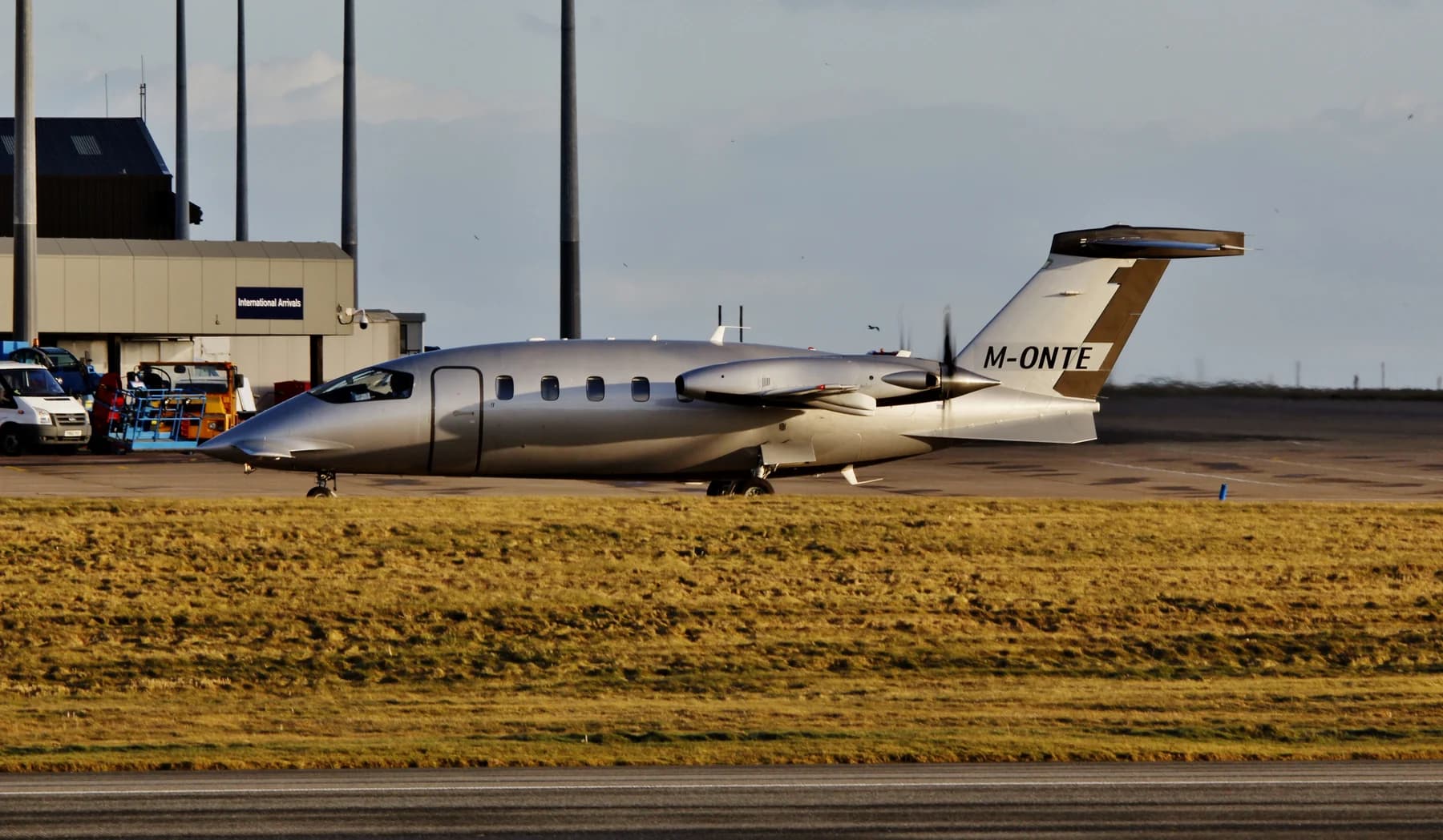 A silver Piaggio P.180 Avanti marked M-ONTE seen in side profile at Sumburgh, with its small forward surface and rear-mounted propellers visible.