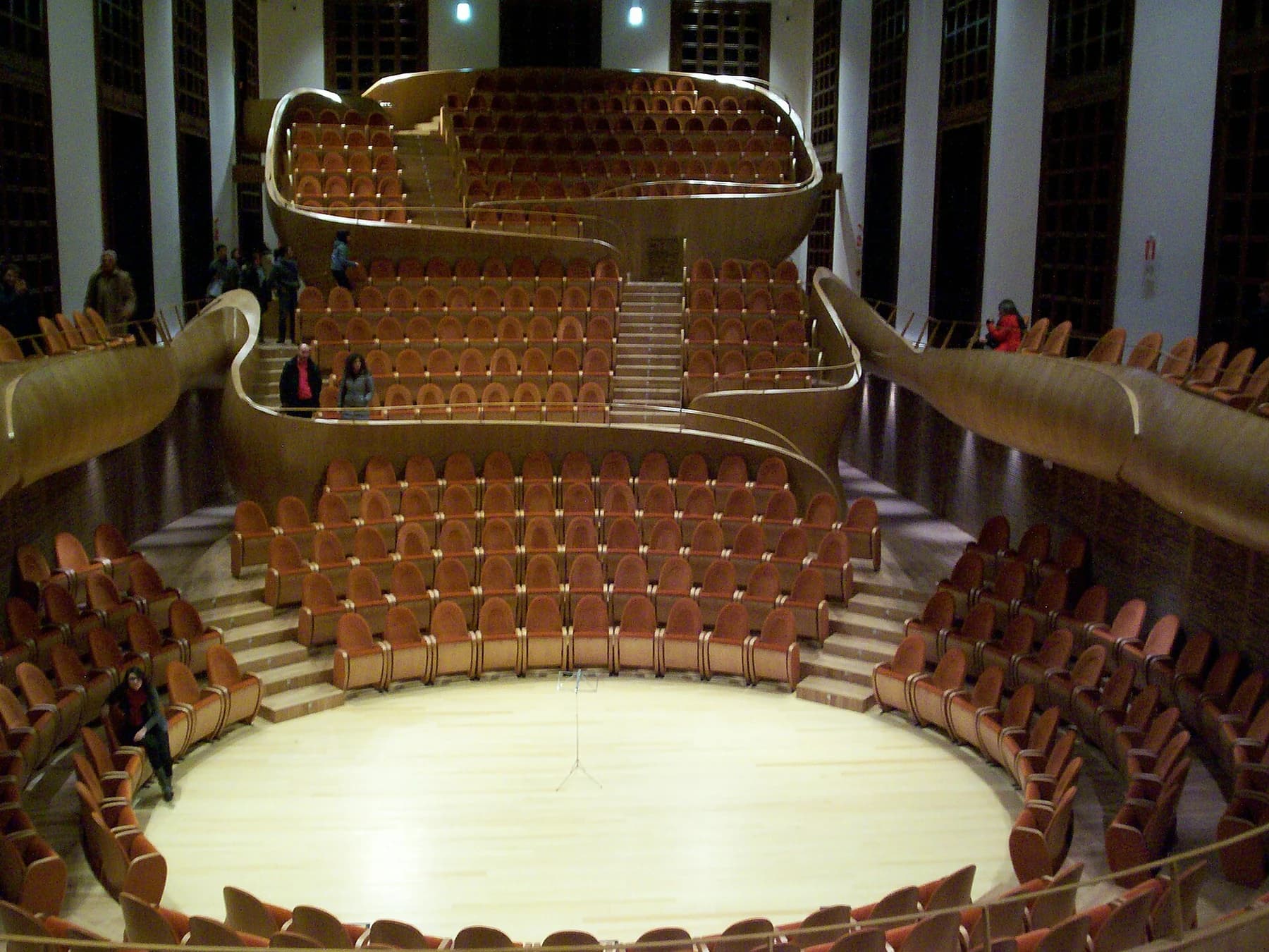 The warm wooden interior of Cremona’s Auditorium Giovanni Arvedi, with curved seating terraces arranged around a central performance floor.