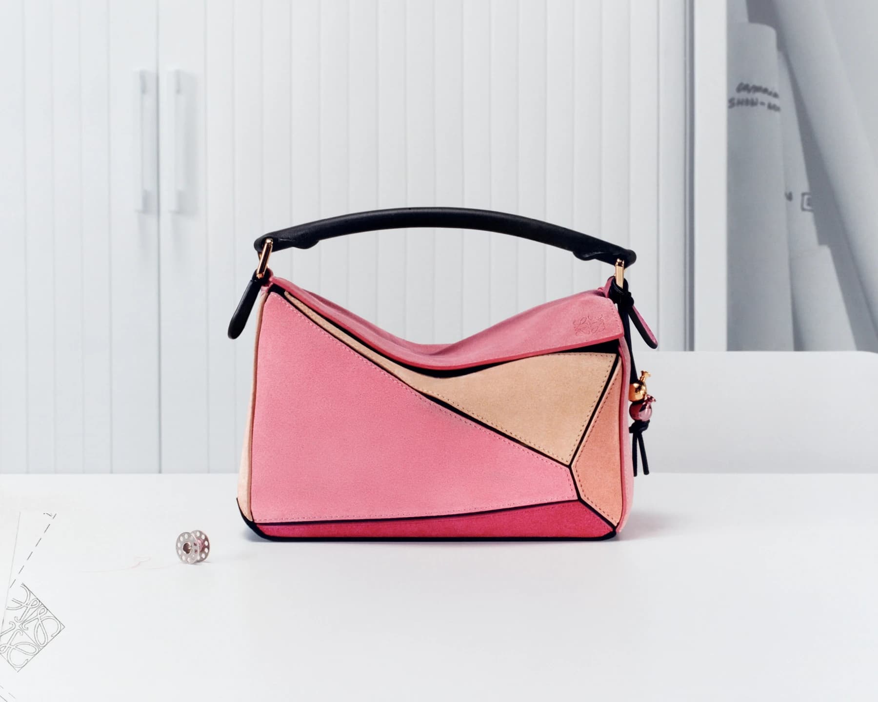 LOEWE’s Puzzle 10 FW15 Runway re-edition in contrasting shades of pink, with its geometric panels and dark handle shown on a pale display surface.