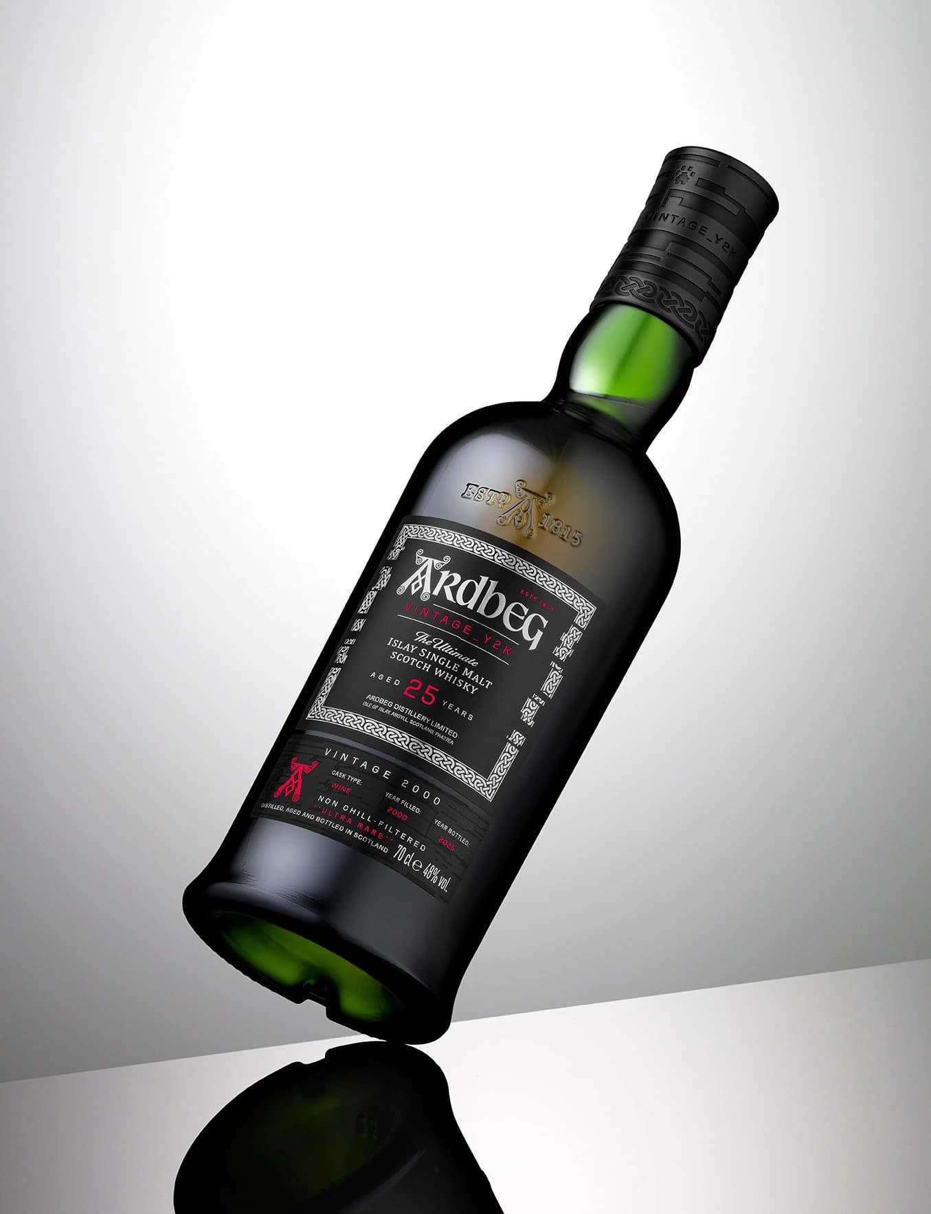 An Ardbeg Y2K 25 Years Old whisky bottle photographed diagonally against a pale background, with its dark green glass and black label visible.