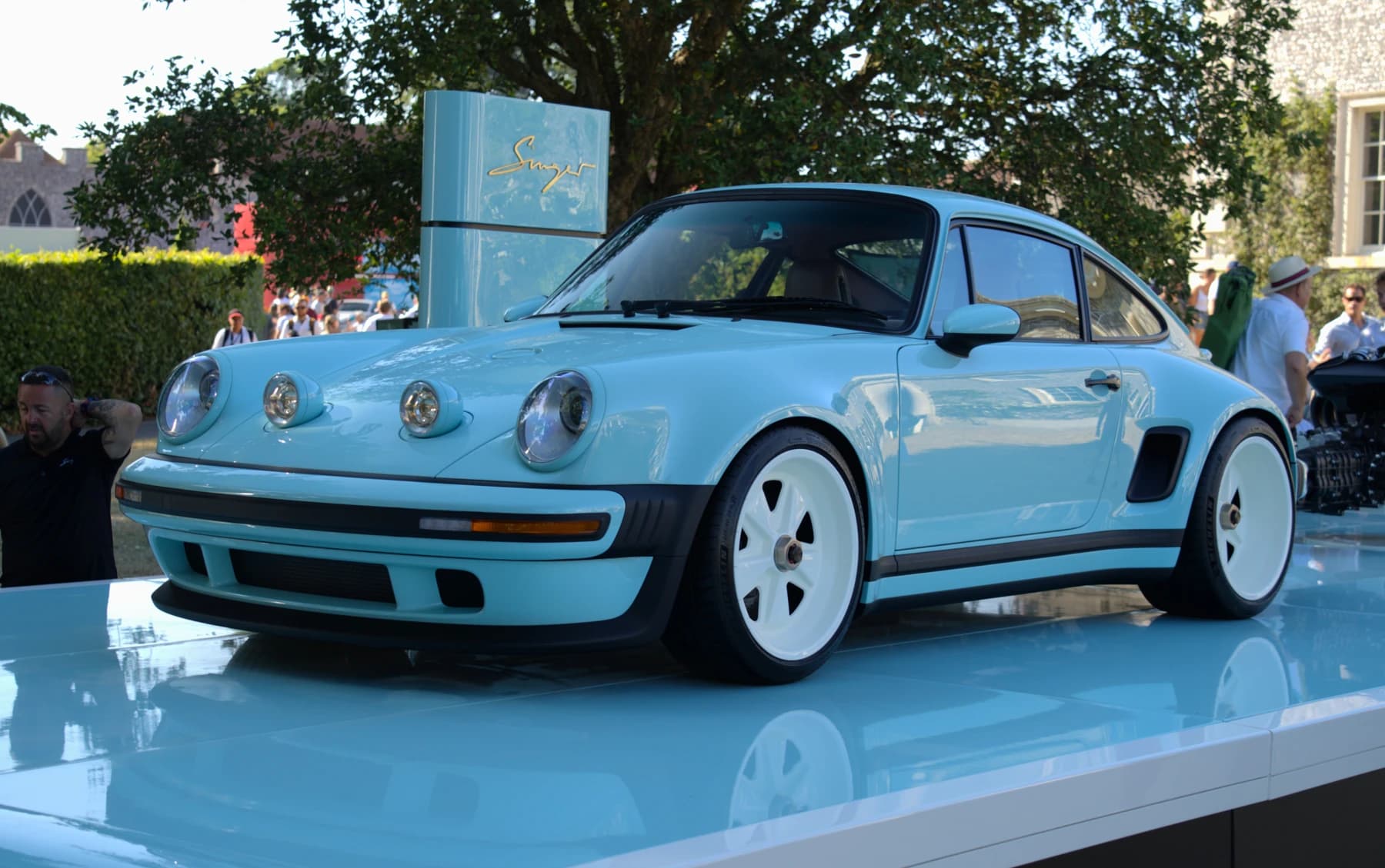 A blue Singer-reimagined 911 Carrera Coupe displayed at Goodwood Festival of Speed, seen from a front three-quarter angle with its pale wheels visible.