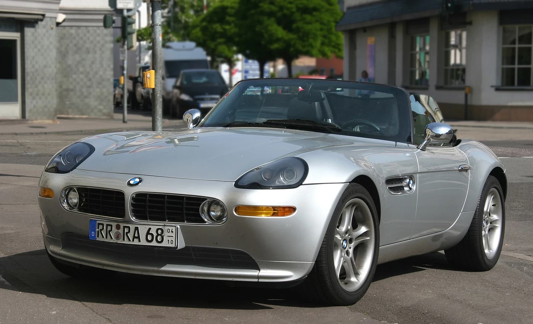 A silver BMW Z8 roadster viewed from the front quarter on a town street, showing its low nose, side vents and open cabin.