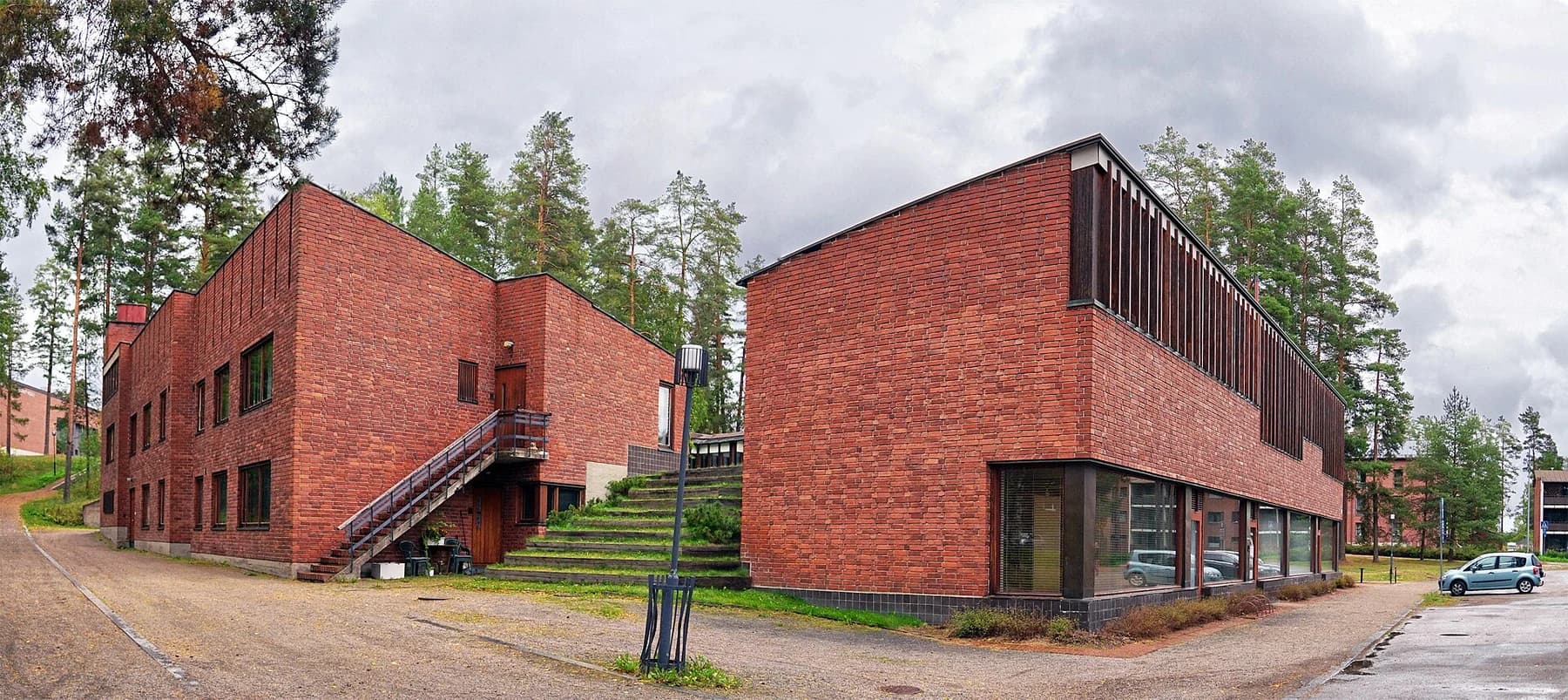 Alvar Aalto’s red brick Säynätsalo Town Hall, with its raised council chamber, exterior steps and trees beneath a cloudy sky.