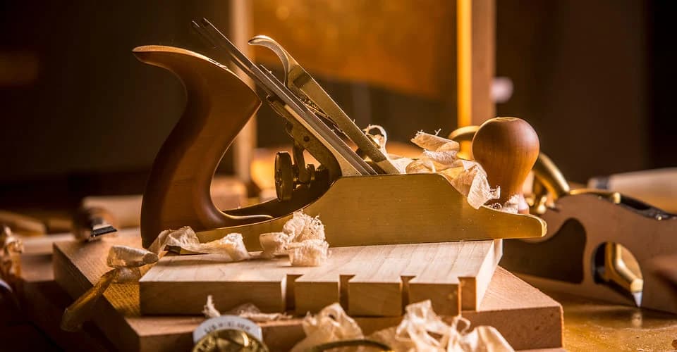 A bronze Lie-Nielsen No.4 smoothing plane among pale wood shavings on a workshop bench.