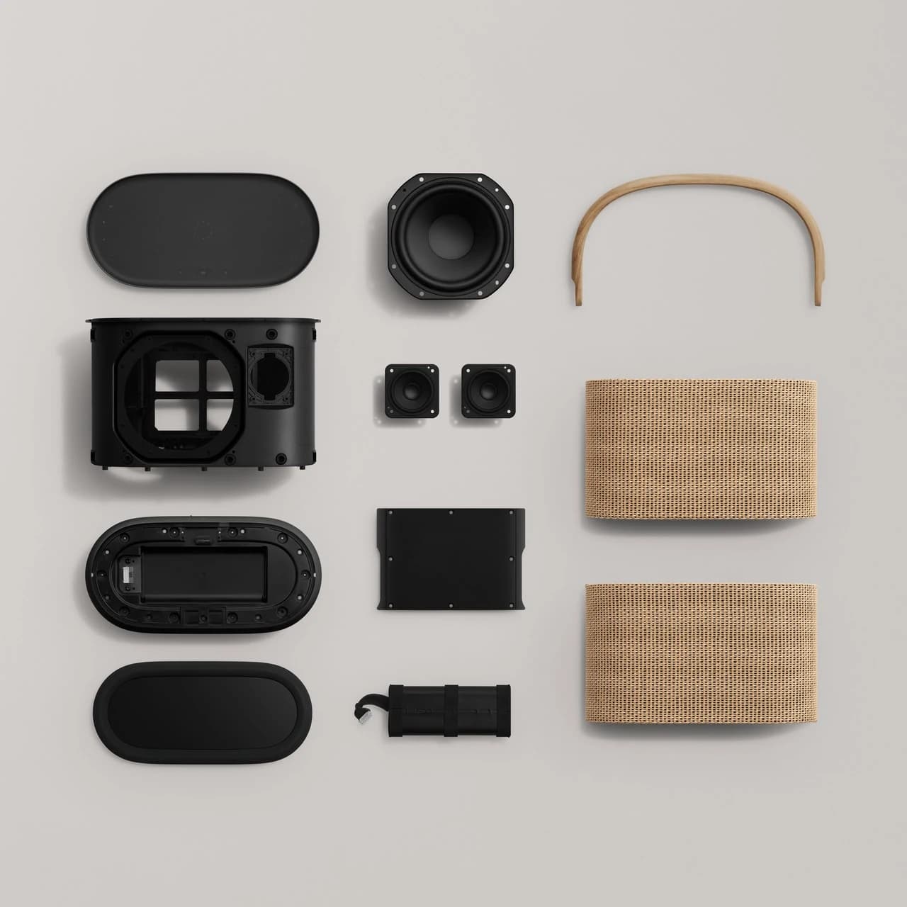 An official disassembled view of Beosound A5 with the wooden handle, woven covers, drivers, base, power supply and internal assemblies arranged on a pale surface.