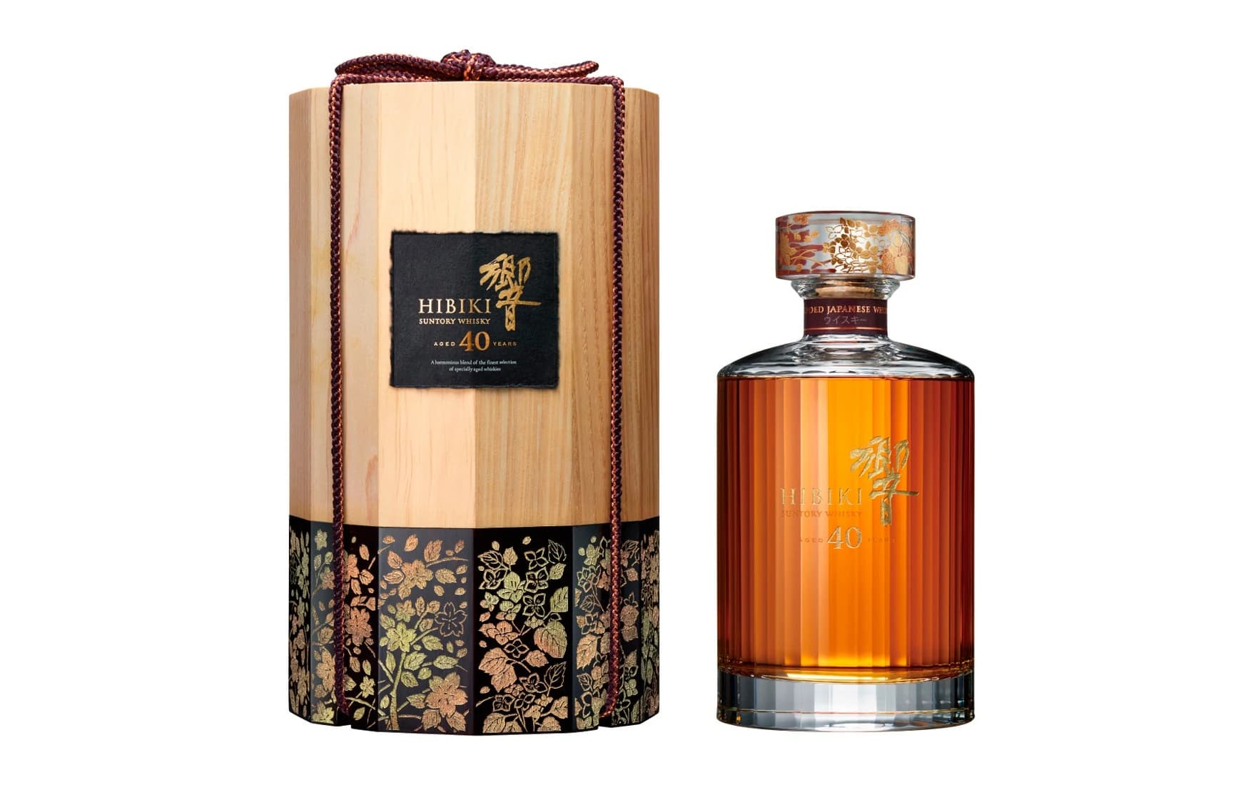 A full Hibiki 40 Years Old crystal whisky bottle with an amber liquid and decorated cap beside its tall twelve-sided wooden presentation box on white.