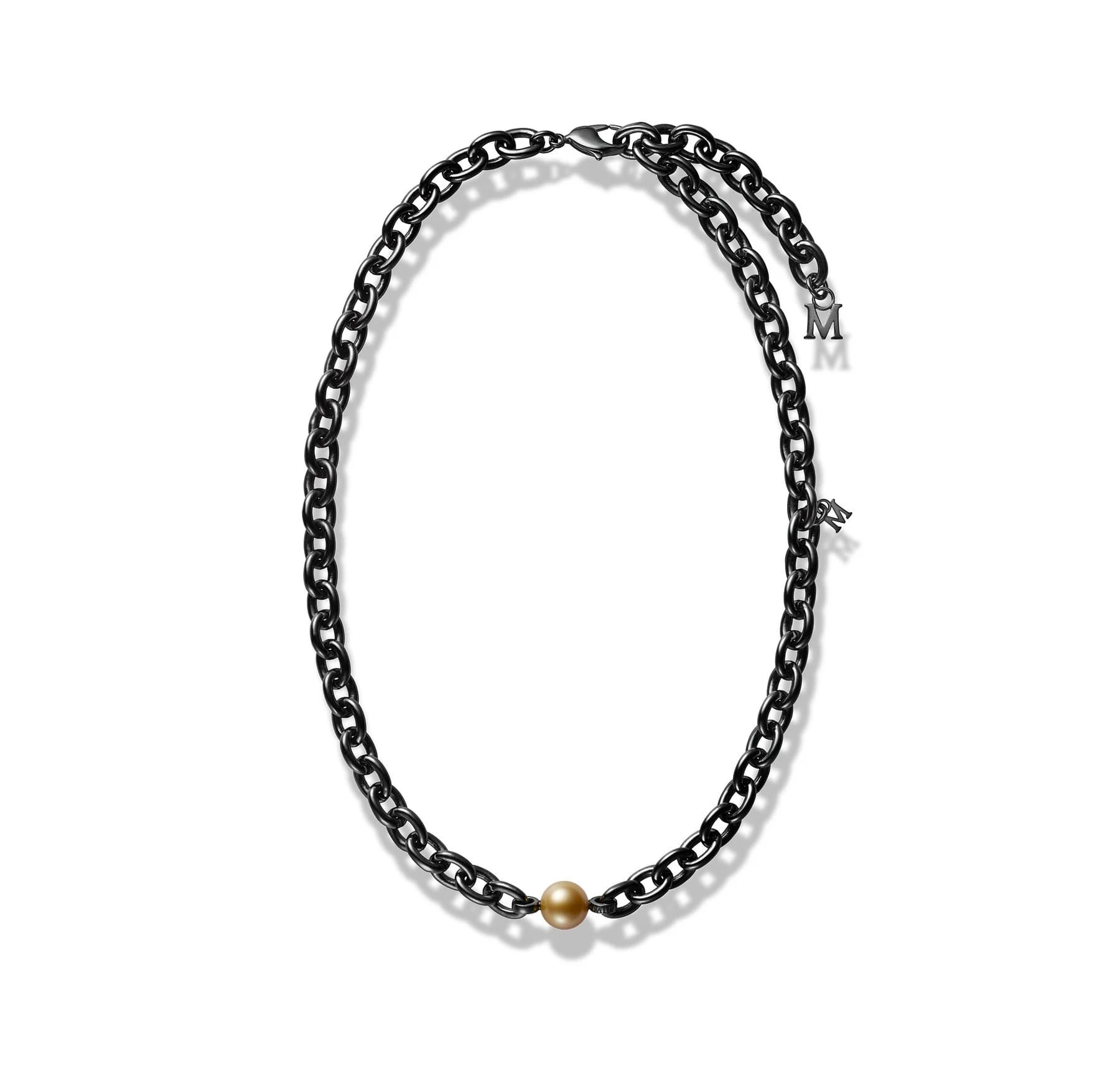 A complete Mikimoto PASSIONOIR necklace on white, with a single golden pearl at the base of a dark silver chain and a small M charm near the fastening.