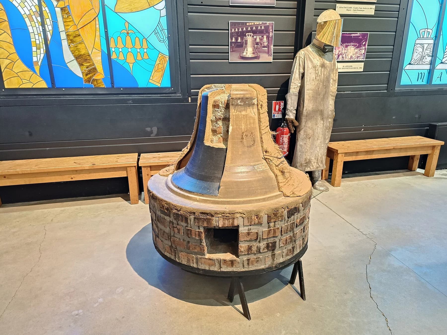 A cutaway bell-making display inside the Paccard museum, revealing layered mould construction beside a protective working outfit.