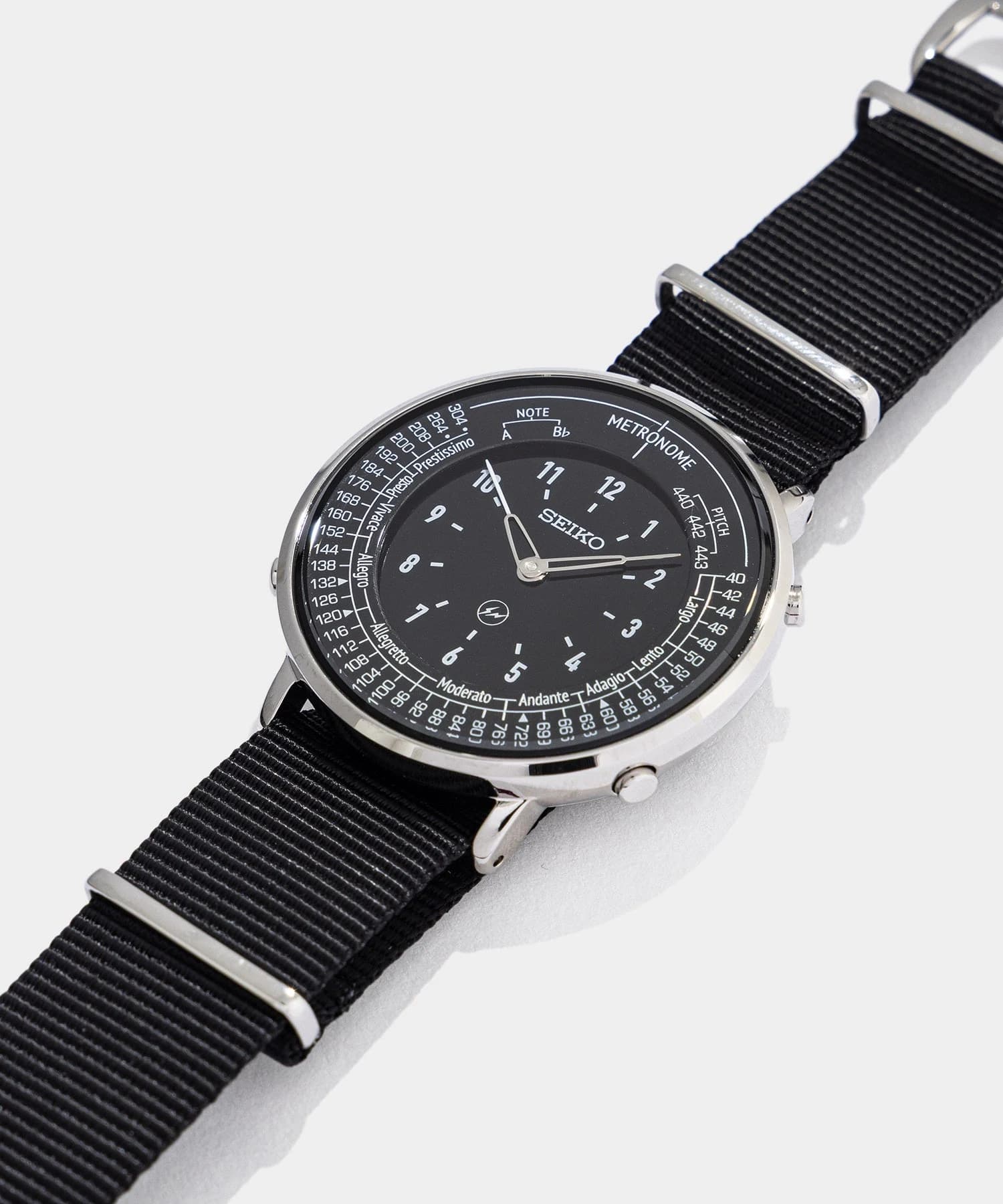 A black-dial Seiko Metronome Watch FRAGMENT edition at an angle, with tempo markings around the dial and a black nylon strap.