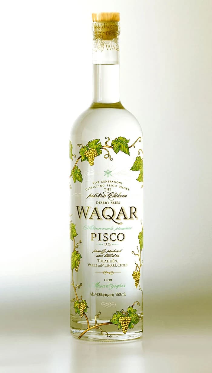 A tall clear bottle of Waqar pisco with a gold cap and illustrated green grapevines against a pale background.
