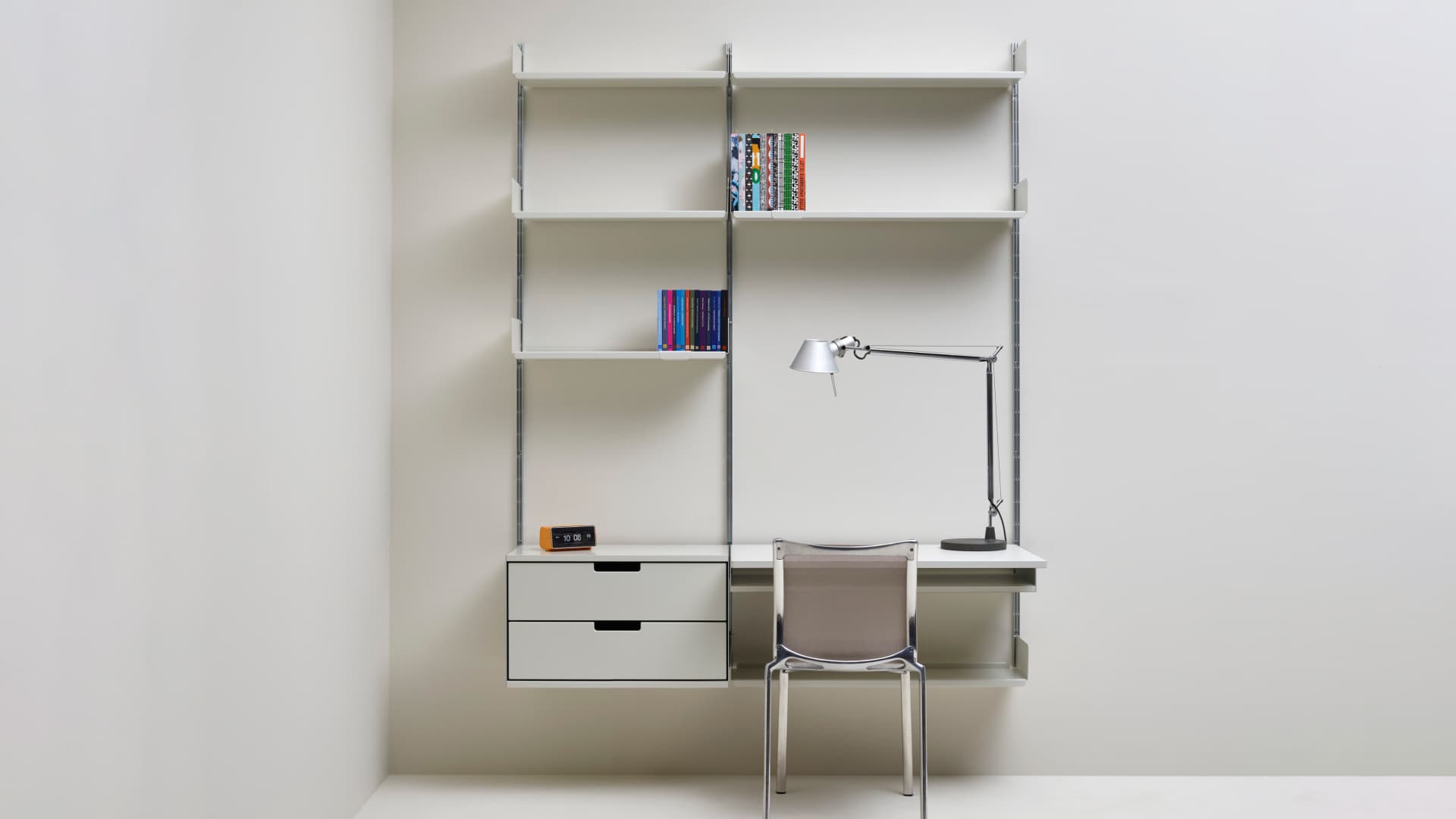 Vitsœ 606 shelving with books, cabinets and a work surface in a bright, restrained interior.