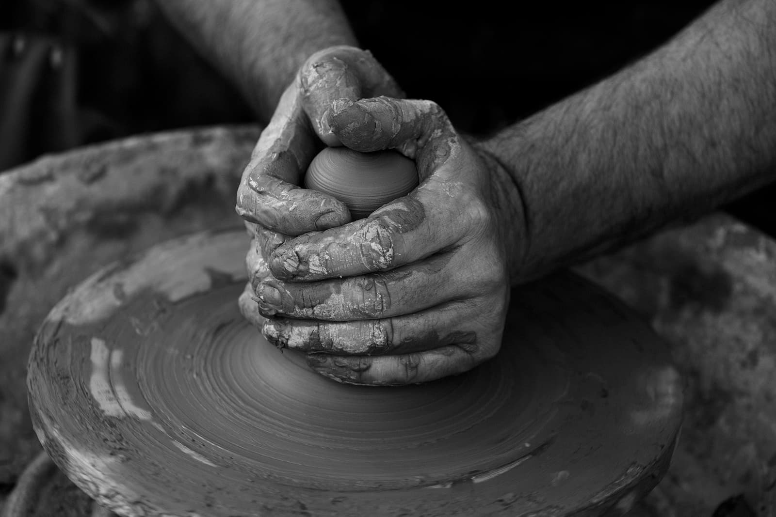 Hands working clay on a pottery wheel.