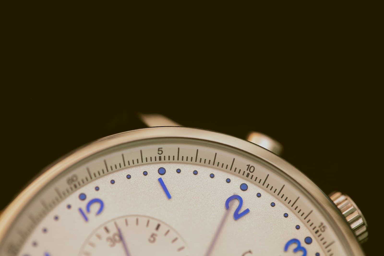A close detail of a watch dial and crown.